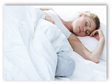 Woman sleeping under covers in her bed.