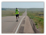 Photo of a skateboarder going along the highway across the plains.