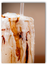 Photo of a milkshake with streaks of chocolate inside the glass and running down the outside, too.