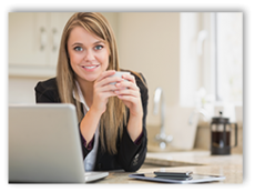 Photo of young woman holding a coffee cup next to her laptop in her kitchen