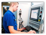 young man looking at computer screen in machine shop