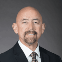 A man in a suit in front of a gray background
