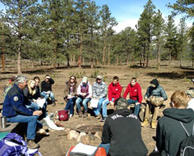 Students discuss the effects of forest management while sitting within the newly restored Ponderosa Forest.
