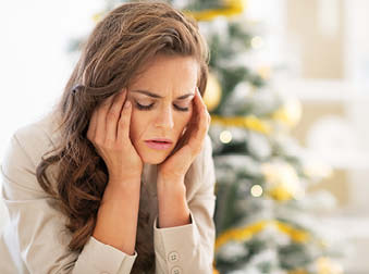 woman stressed out sitting in front of a holiday tree
