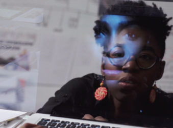 Photo of Joy Buolamwini (reflected in a computer screen)