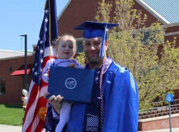 Chris holding his daughter at graduation