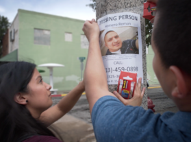 People putting up missing person poster