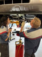 automotive apprentice working on the underside of a car