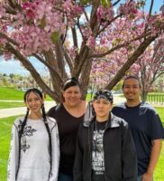 The Salazar siblings with their aunt Angelica standing in front of a tree with pink flowers