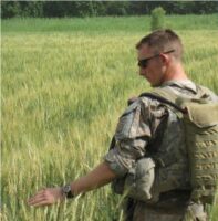 Andrew standing in a field wearing Army fatigues